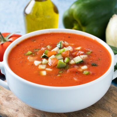 Traditional Spanish gazpacho soup in bowl on blue background